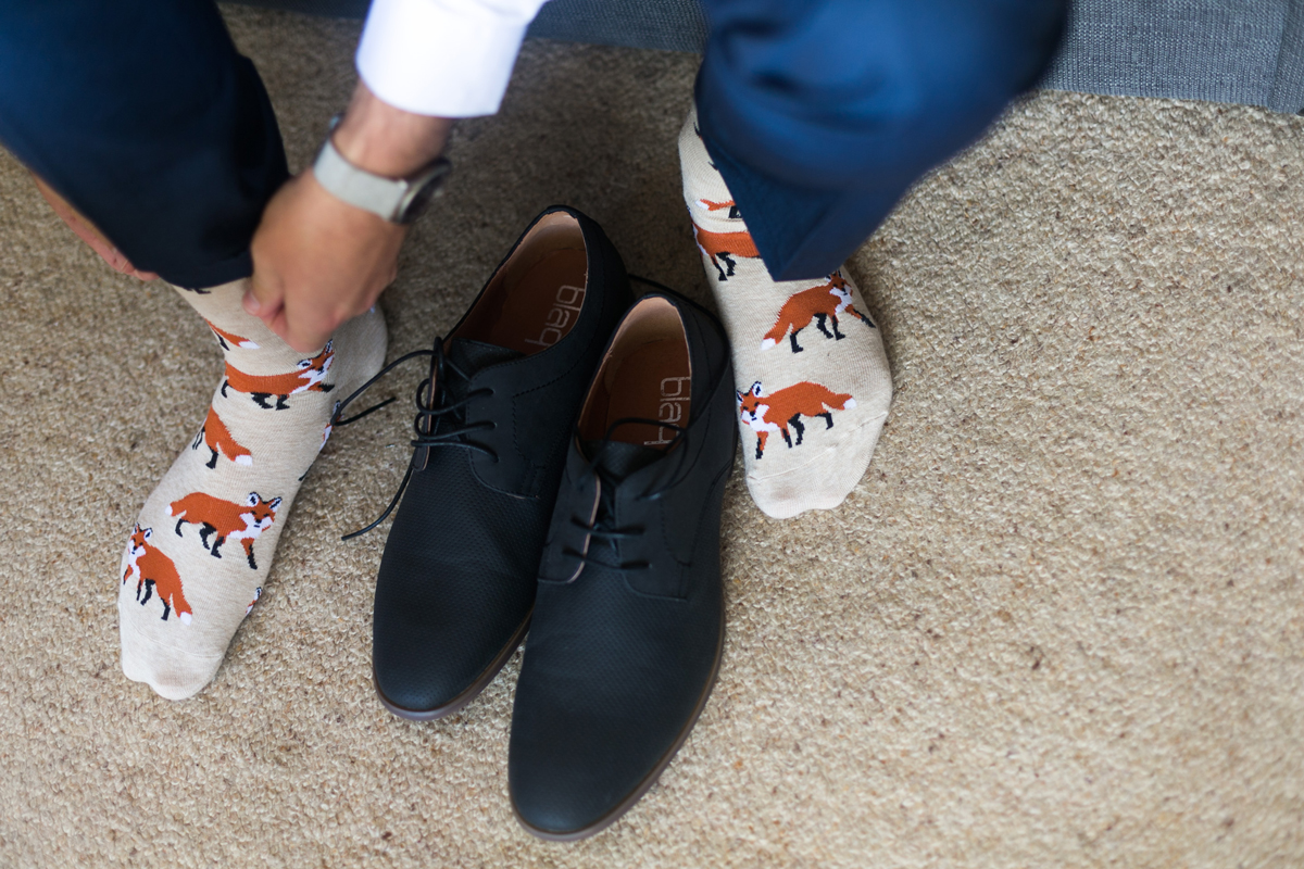 Close up of the groom's navy lace-up shoes and fox print socks as he gets ready for his Tocal Homestead wedding photographer