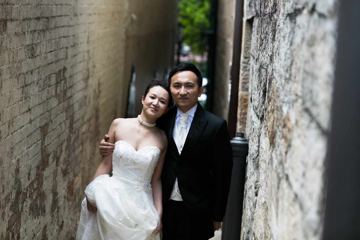 The bride and groom standing with their arms around each other in an old brick and sandstone alleyway in The Rocks Sydney wedding photographer