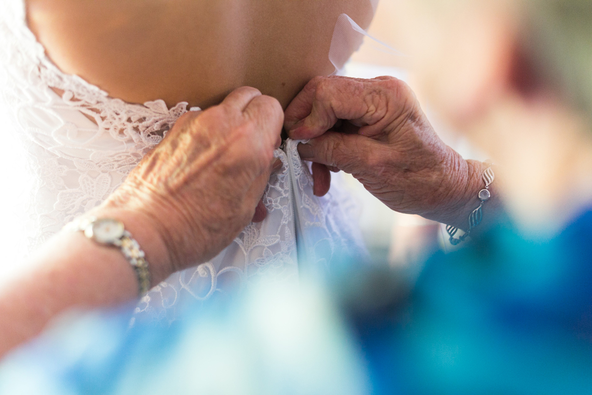 Close up of the bride's grandmother buttoning up the back of her white lace wedding dress Tocal Homestead wedding photographer