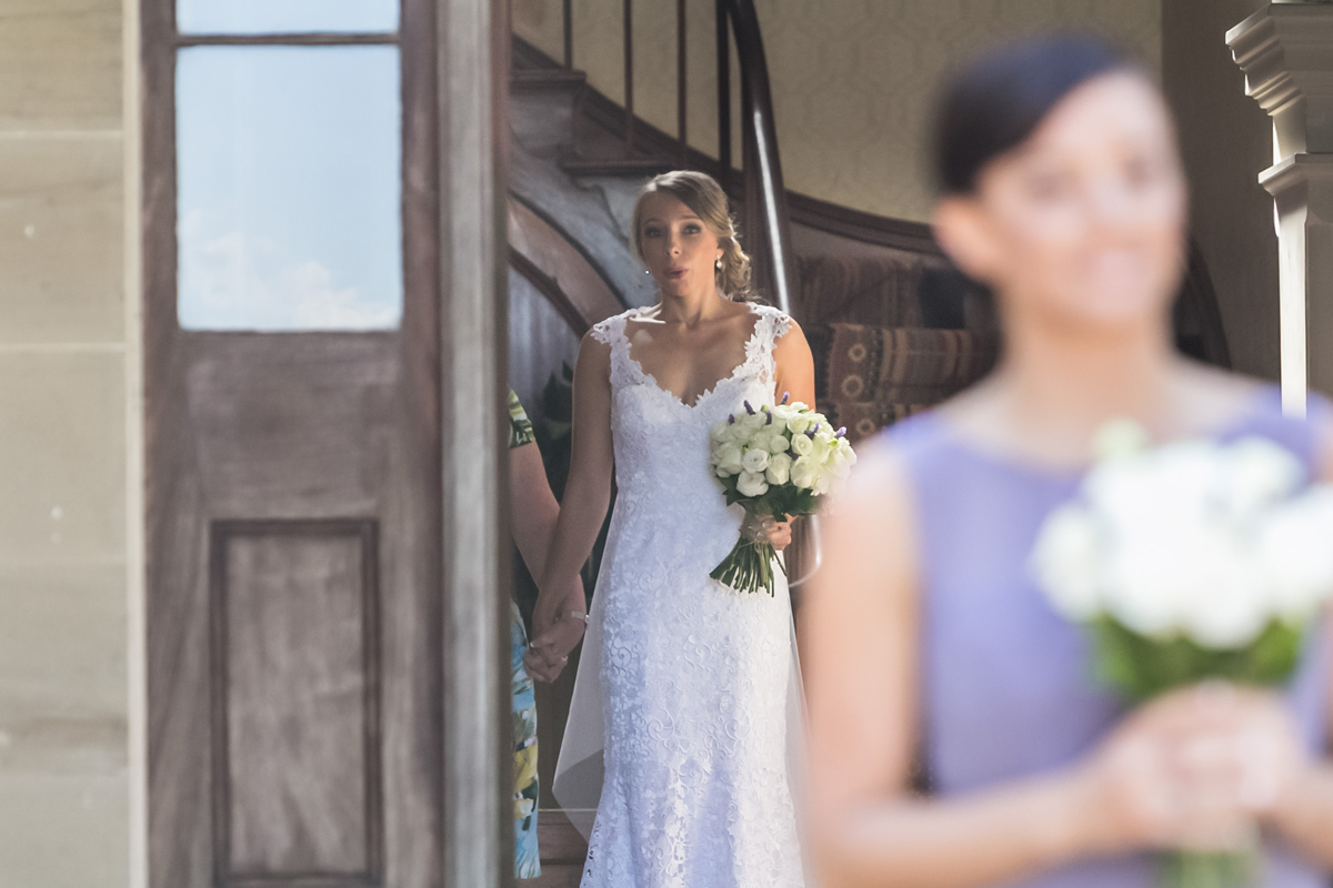 Candid shot over the bridesmaid's shoulder as the bride takes a deep breath before walking down the aisle at her Tocal Homestead wedding photographer